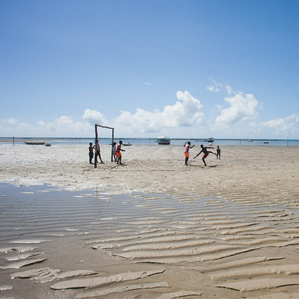 niños jugando futbol en playa con la marea baja